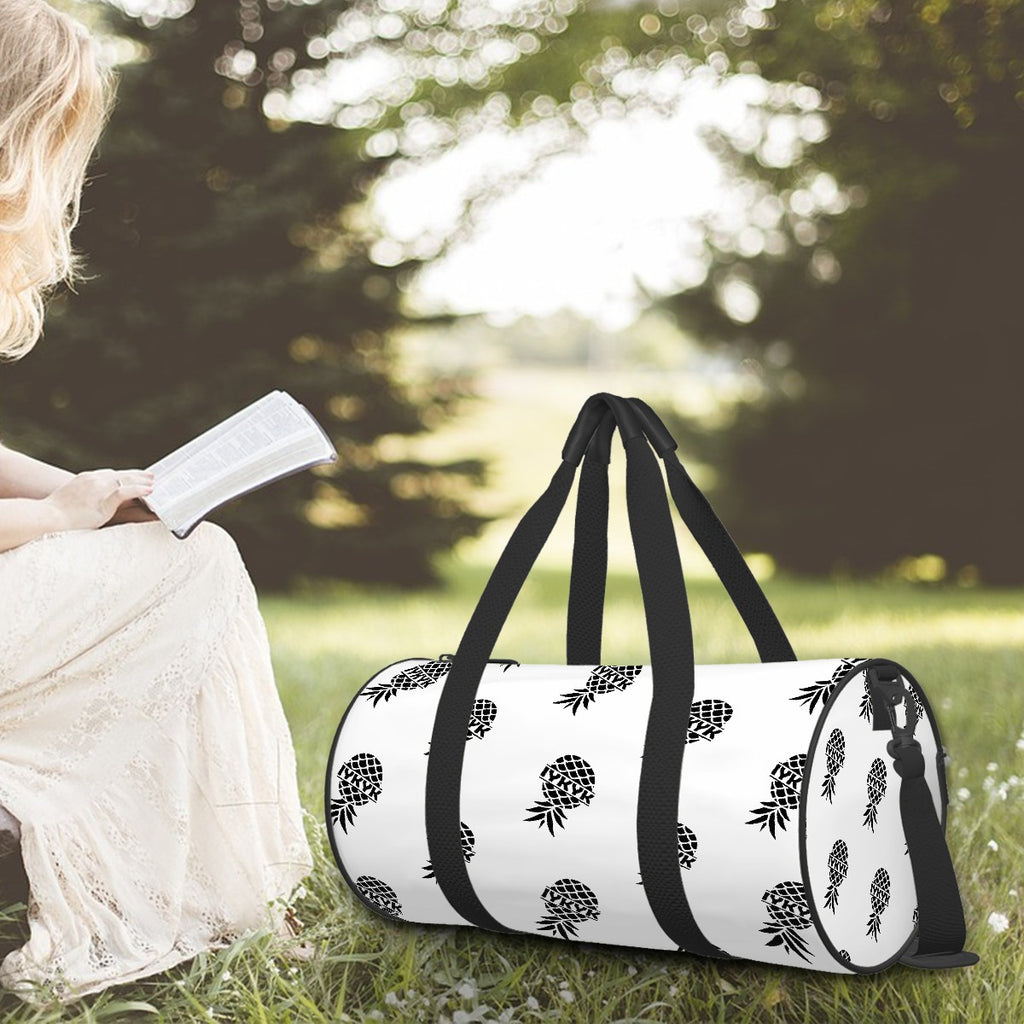 Swinger inspired dufflebag with an upside down pineapple with IYKYK on the inside of it sitting on the ground next too a woman reading a book.