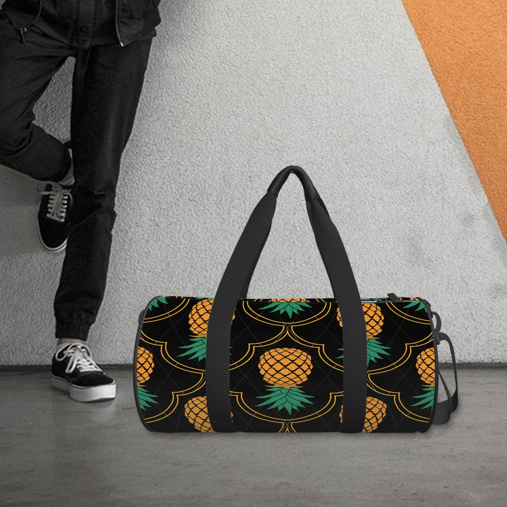 Luxury upside down pineapple bag in black and yellow sitting on the ground next to someone in dark colored clothing with one leg on the wall.